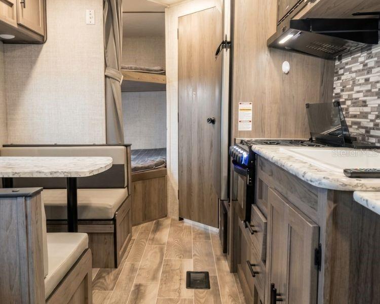 A travel trailer interior featuring a dinette, a kitchen with wood cabinets, and bunk beds — CARR 662 KM 2.1,  SANTANA, PR 00612, ARECIBO, PR