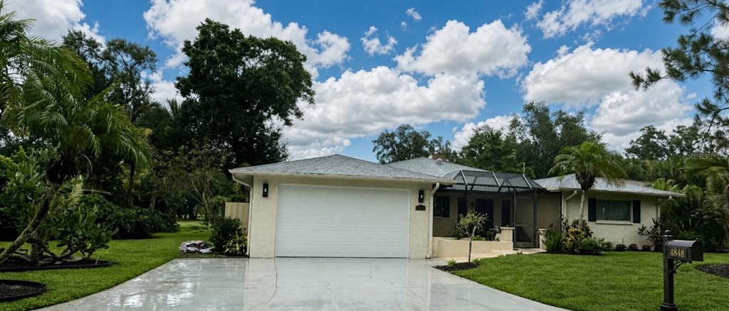 A single-story house with a white garage, a screened-in porch, and a green lawn — 4848 HAWKSHEAD PARK, SARASOTA, FL