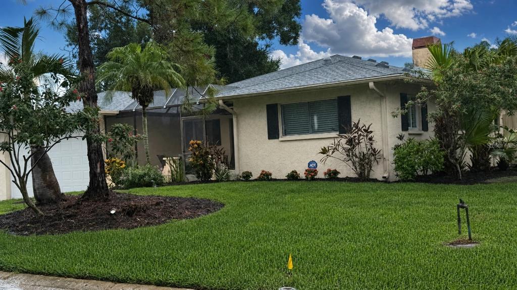 A single-story house with a screened-in porch, a white garage door, and a grassy lawn — 4848 HAWKSHEAD PARK, SARASOTA, FL