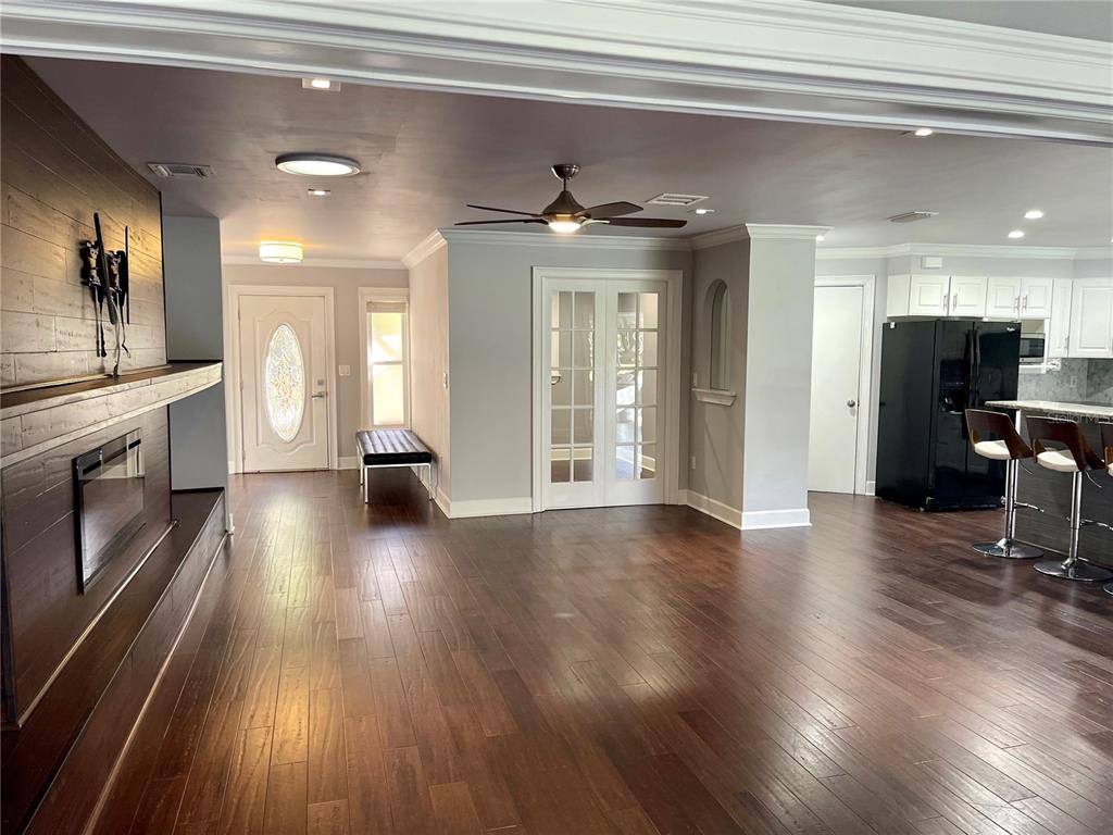 A living area features dark wood flooring, a fireplace with a wood-paneled wall, and kitchen — 4848 HAWKSHEAD PARK, SARASOTA, FL