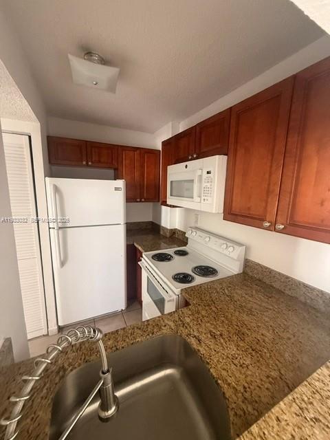 A kitchen features wood cabinets, granite countertops, a white refrigerator, and a stainless steel sink — 8145 NW 7th St # 406, Miami FL 33126, MIAMI, FL