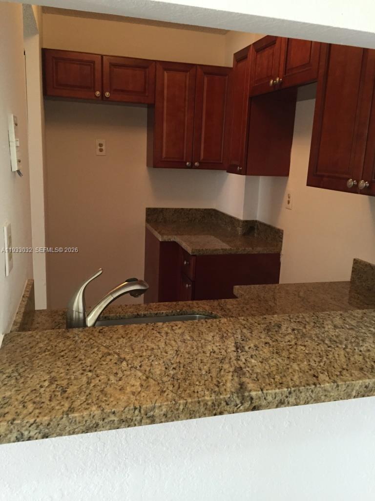 A kitchen features dark wood cabinets, granite countertops, and a stainless steel sink — 8145 NW 7th St # 406, Miami FL 33126, MIAMI, FL