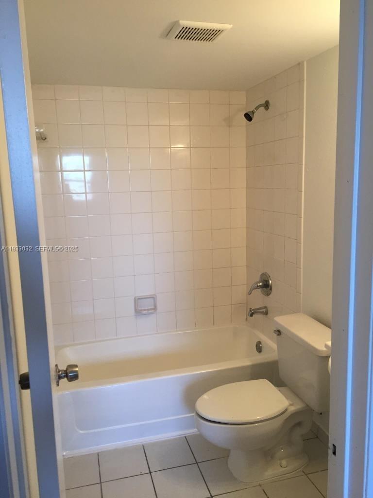 A bathroom features a white bathtub with a showerhead, tiled walls, and a toilet — 8145 NW 7th St # 406, Miami FL 33126, MIAMI, FL