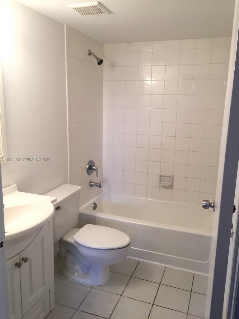 A bathroom features a white vanity, a toilet, and a shower-tub combo with white tiles — 8145 NW 7th St # 406, Miami FL 33126, MIAMI, FL