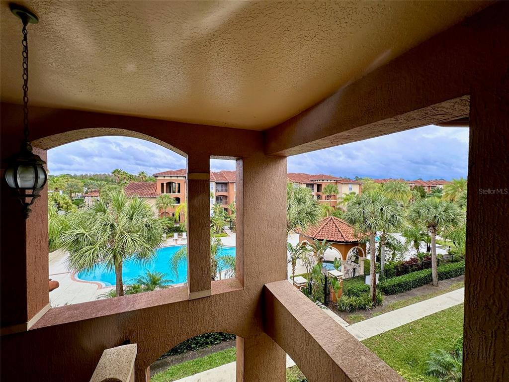 A view from a covered balcony overlooking a swimming pool and surrounding apartment buildings — 5578 METROWEST BOULEVARD UNIT 1-302, ORLANDO, FL