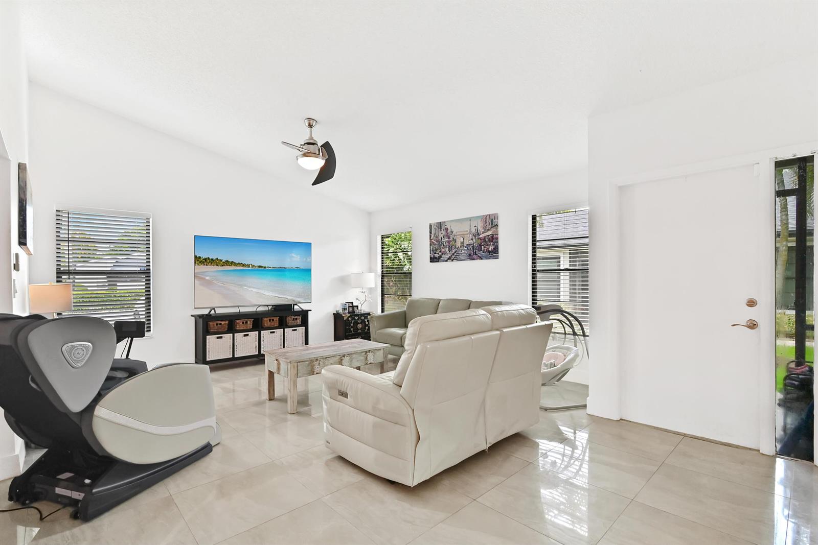 A living room features white walls, tile flooring, a television, and light-colored furniture — 4383 Willow Pond Circle, West Palm Beach FL 33417, WEST PALM BEACH, FL