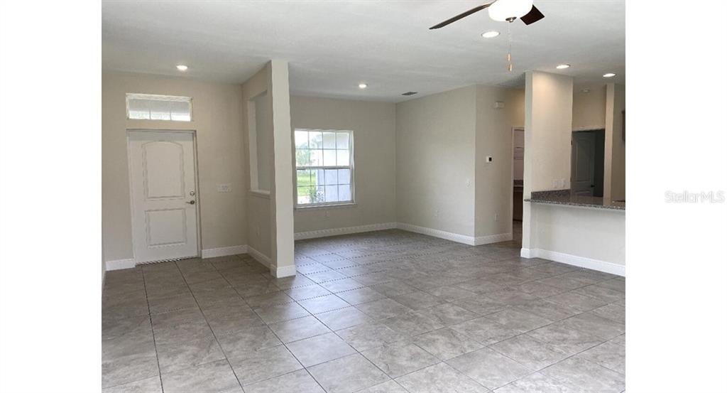 An open-concept living area features light-colored tile flooring, neutral walls, and a kitchen breakfast bar — 5961 GOTTFRIED LANE, NORTH PORT, FL