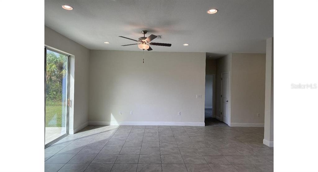 A living room with tile flooring, a ceiling fan, recessed lighting, and a sliding glass door — 5961 GOTTFRIED LANE, NORTH PORT, FL