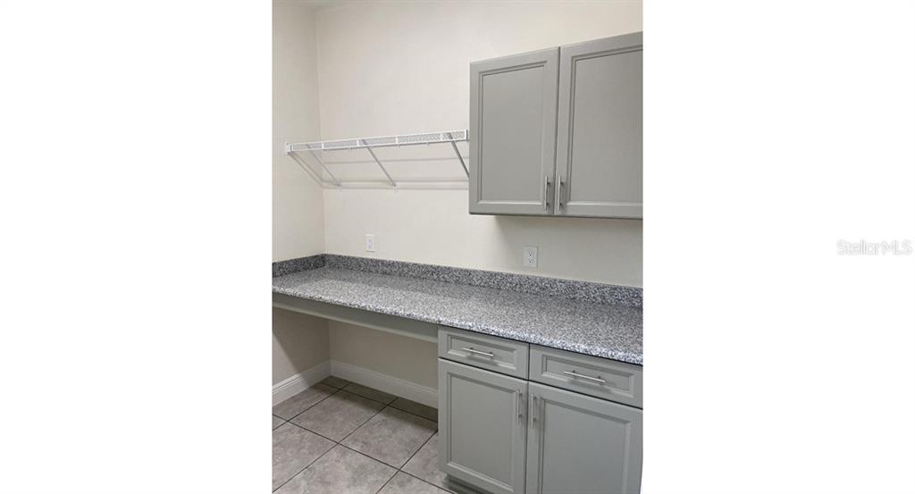 A laundry room features gray cabinets, a granite countertop, and a white wire shelf — 5961 GOTTFRIED LANE, NORTH PORT, FL