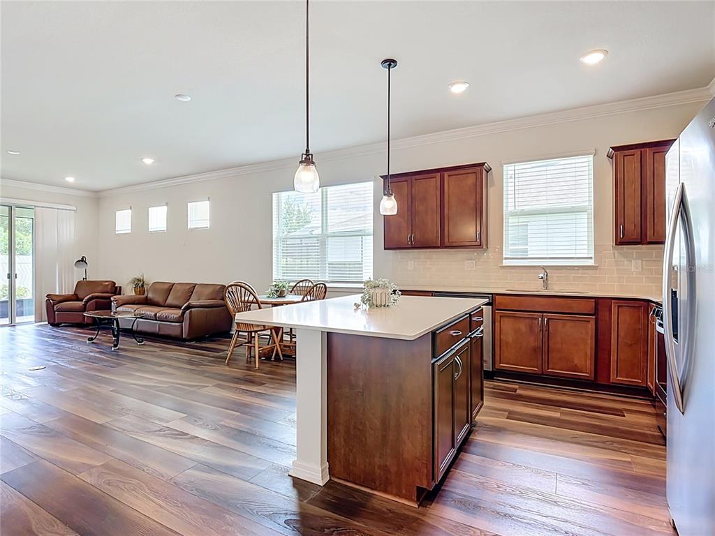 An open-concept kitchen and living area features dark wood cabinets, an island, and wood flooring — 2949 CHERRY BLOSSOM LOOP, ST CLOUD, FL