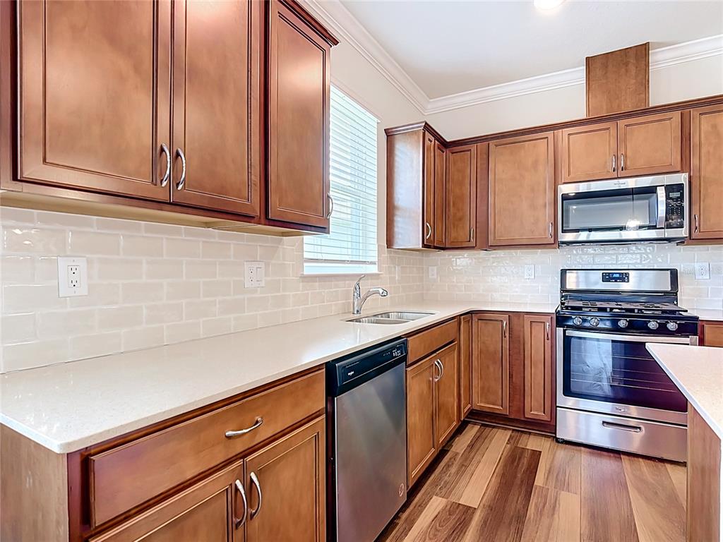 A kitchen features wood cabinets, stainless steel appliances, white countertops, and a subway tile backsplash — 2949 CHERRY BLOSSOM LOOP, ST CLOUD, FL