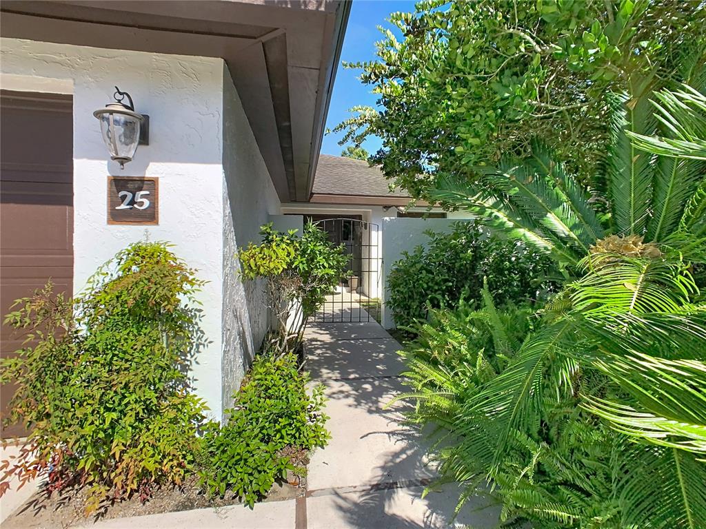 A walkway leads to a gated entrance beside a house with a number 25 sign — 25 HUNTLEY COURT, HAINES CITY, FL