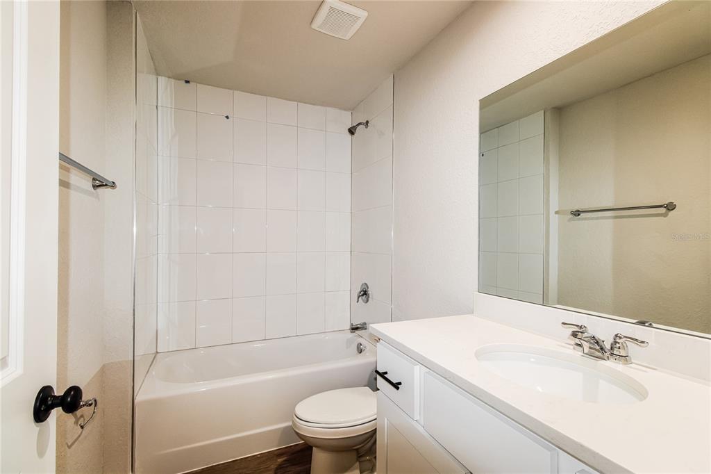 A bathroom features a white vanity, a mirror, and a shower-tub combination with white tiles — 5953 W OAK PARK BOULEVARD, HOMOSASSA, FL