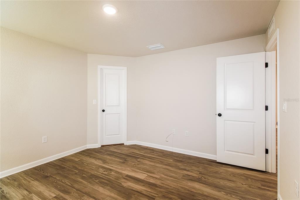 An empty room with light-colored walls, white doors, and wood-look flooring — 5953 W OAK PARK BOULEVARD, HOMOSASSA, FL