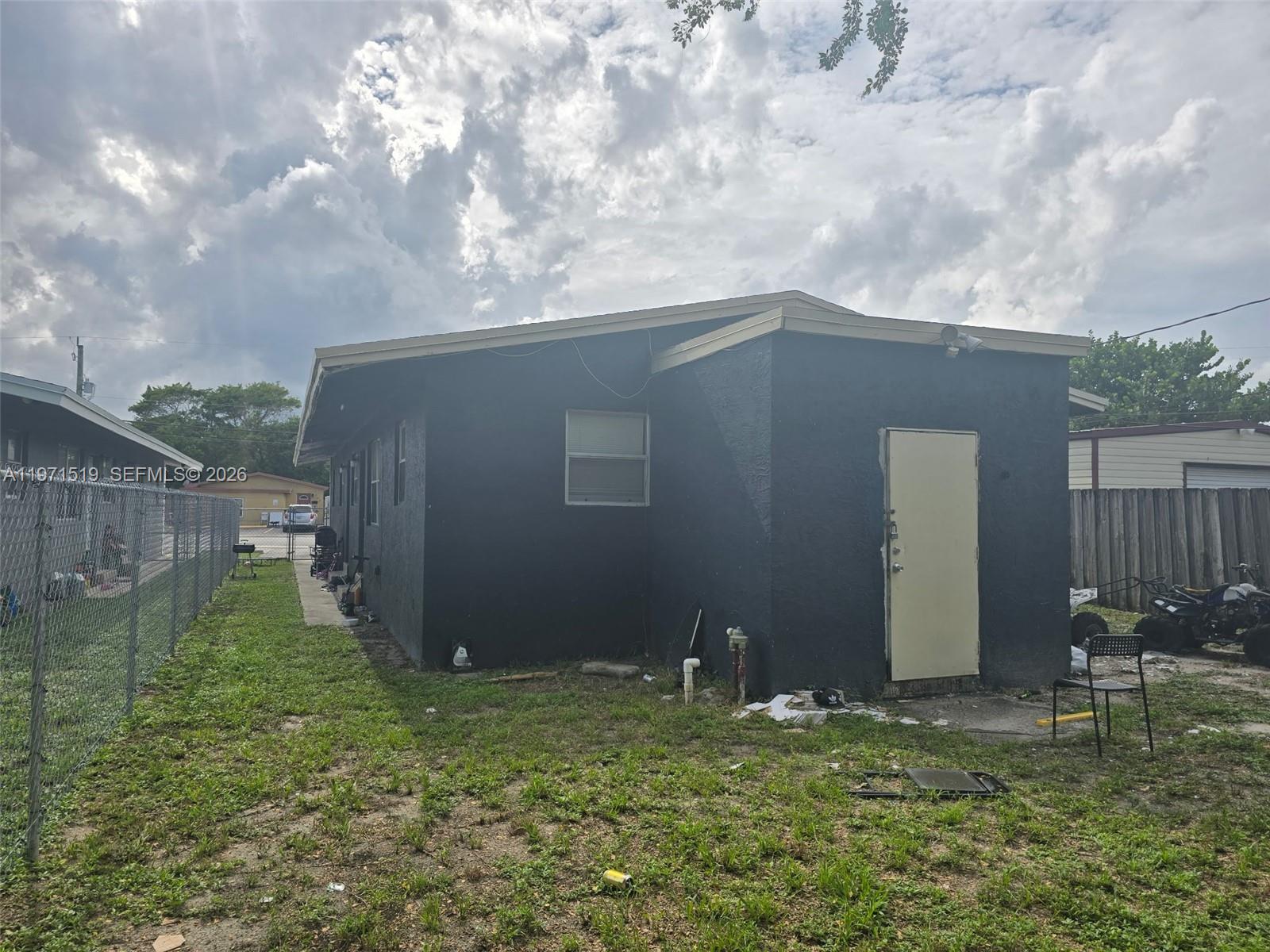 The exterior of a dark-painted house features a single door, a window, and a chain-link fence — 770 SW 2nd Ave, Deerfield Beach FL 33441, DEERFIELD BEACH, FL