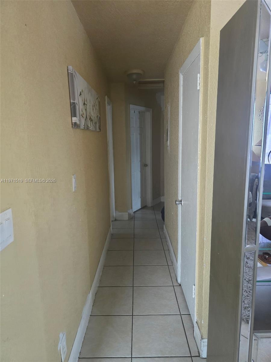 A narrow hallway features beige walls, white doors, and light-colored square floor tiles — 770 SW 2nd Ave, Deerfield Beach FL 33441, DEERFIELD BEACH, FL
