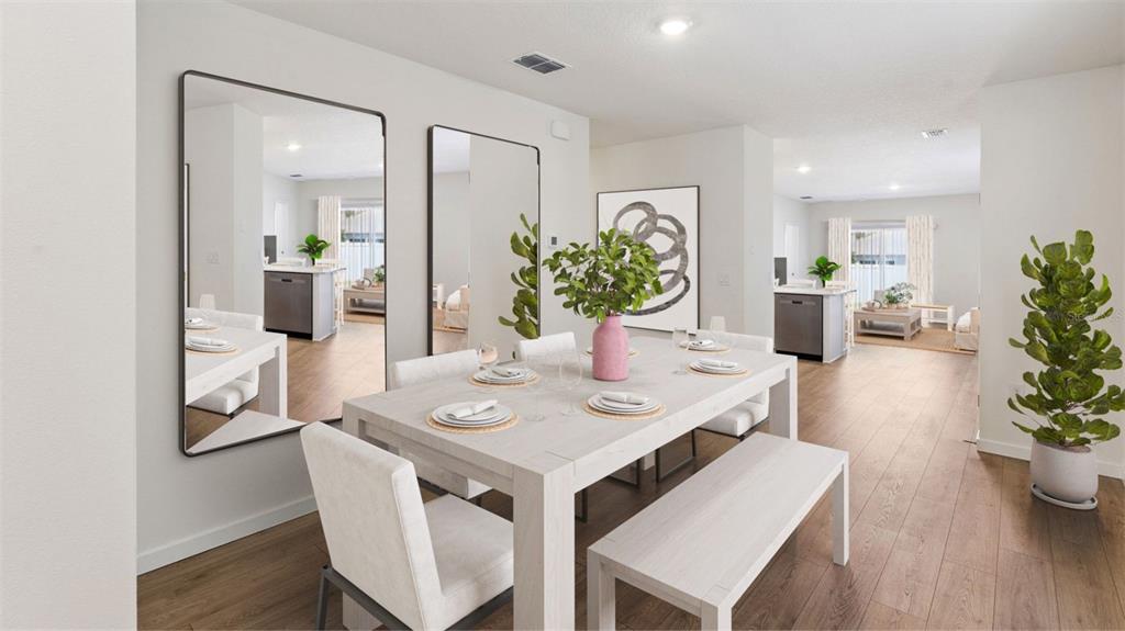 A dining room features a light wood table, upholstered chairs, a bench, and two large mirrors — 3061 HOUSE FINCH ROAD, ST CLOUD, FL