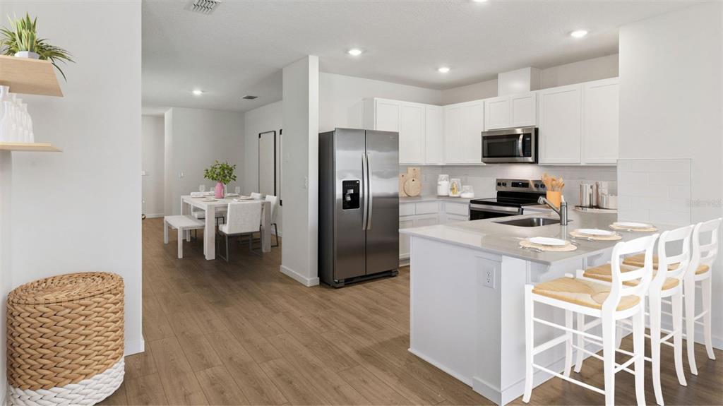 A kitchen with white cabinets and stainless steel appliances opens to a dining area — 3061 HOUSE FINCH ROAD, ST CLOUD, FL