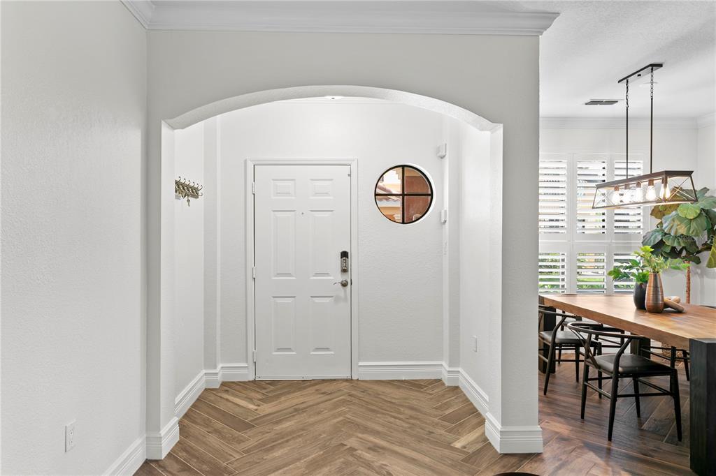 An entryway features a white front door, an arched opening, and herringbone-patterned wood-look flooring — 2741 VIA CIPRIANI UNIT 914A, CLEARWATER, FL