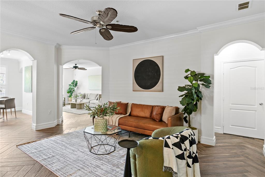 A living room features a leather sofa, a green armchair, and a patterned area rug — 2741 VIA CIPRIANI UNIT 914A, CLEARWATER, FL