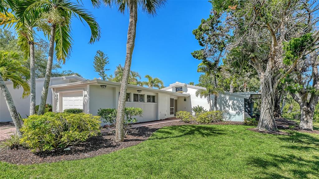 A single-story white house with a garage and palm trees sits on a grassy lawn — 239 HOURGLASS WAY UNIT V7, SARASOTA, FL