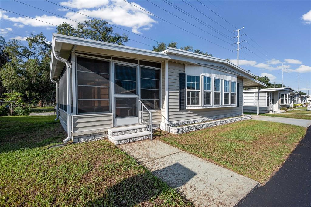 A single-story manufactured home with a screened-in porch and a concrete walkway — 37818 VALENCIA AVENUE, ZEPHYRHILLS, FL