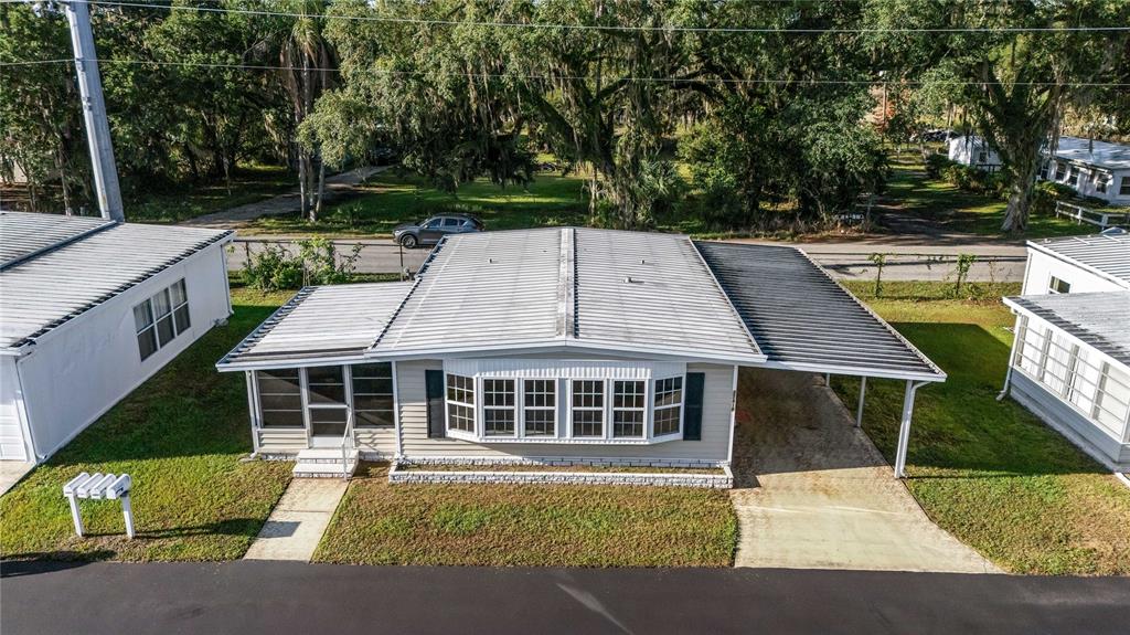An elevated view of a single-story manufactured home with a metal roof and carport — 37818 VALENCIA AVENUE, ZEPHYRHILLS, FL