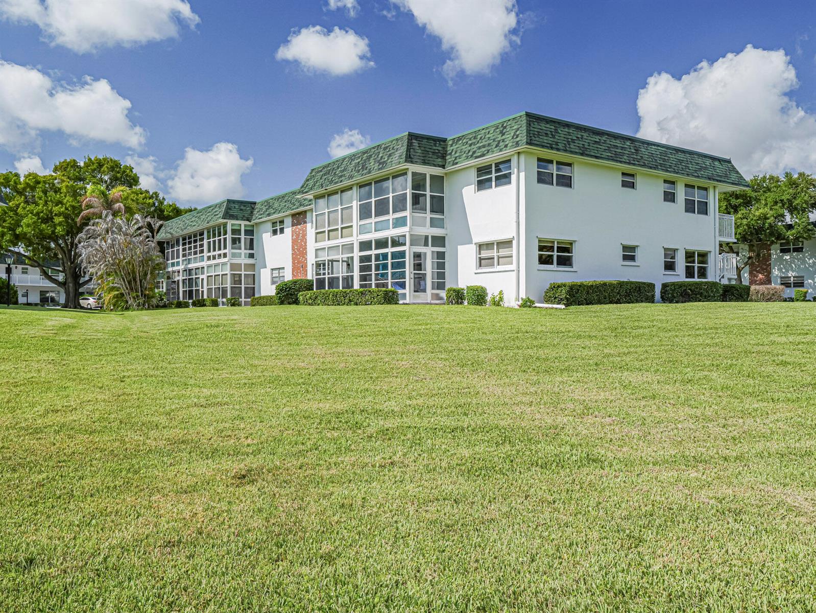 A two-story white apartment building with a green shingled roof sits behind a large lawn — 2800 Indian River Boulevard, Vero Beach FL 32960, VERO BEACH, FL