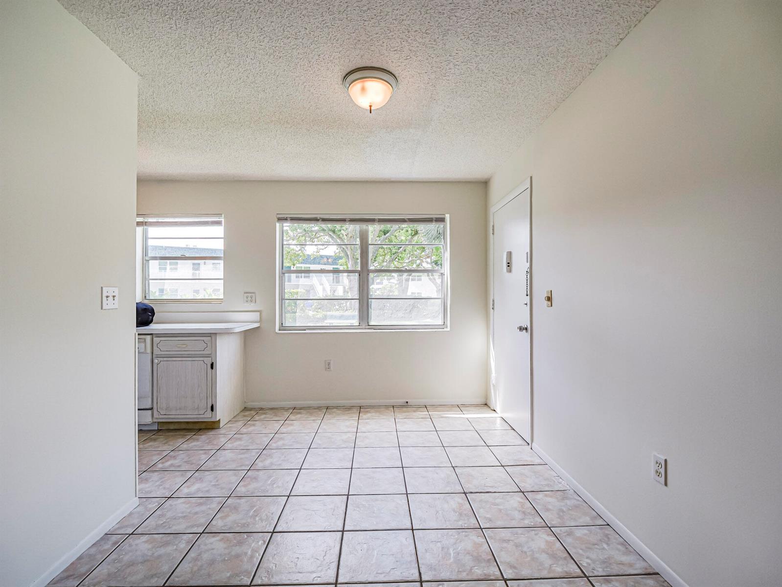 A kitchen with tiled floors, white cabinets, and a window overlooking an exterior building — 2800 Indian River Boulevard, Vero Beach FL 32960, VERO BEACH, FL
