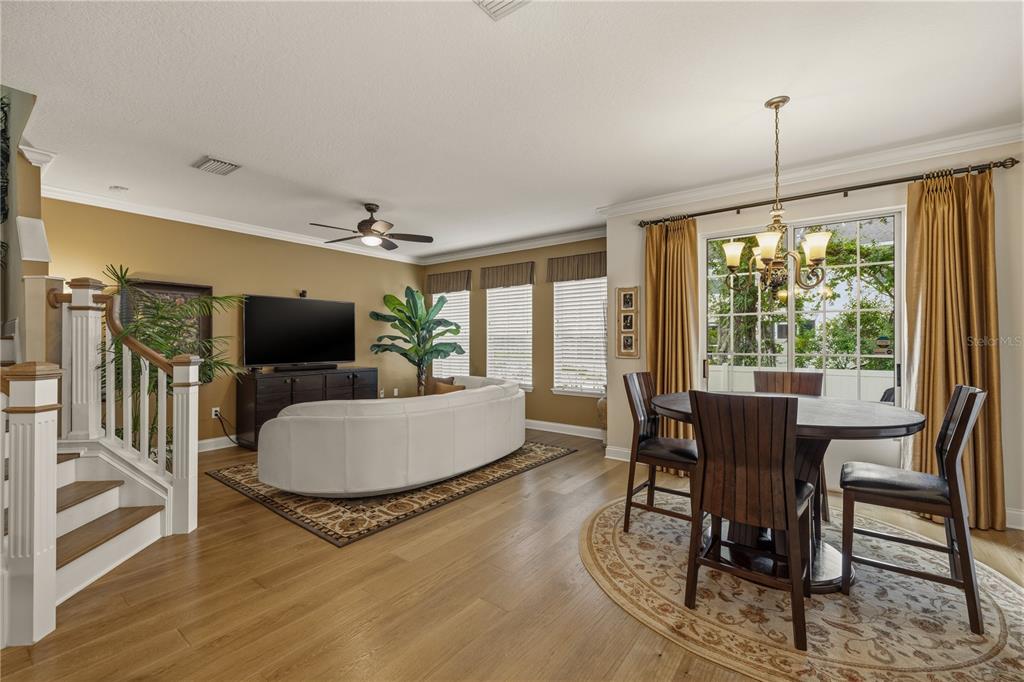 A living and dining area with hardwood floors, a curved white sofa, and a chandelier — 27763 PLEASURE RIDE LOOP, WESLEY CHAPEL, FL