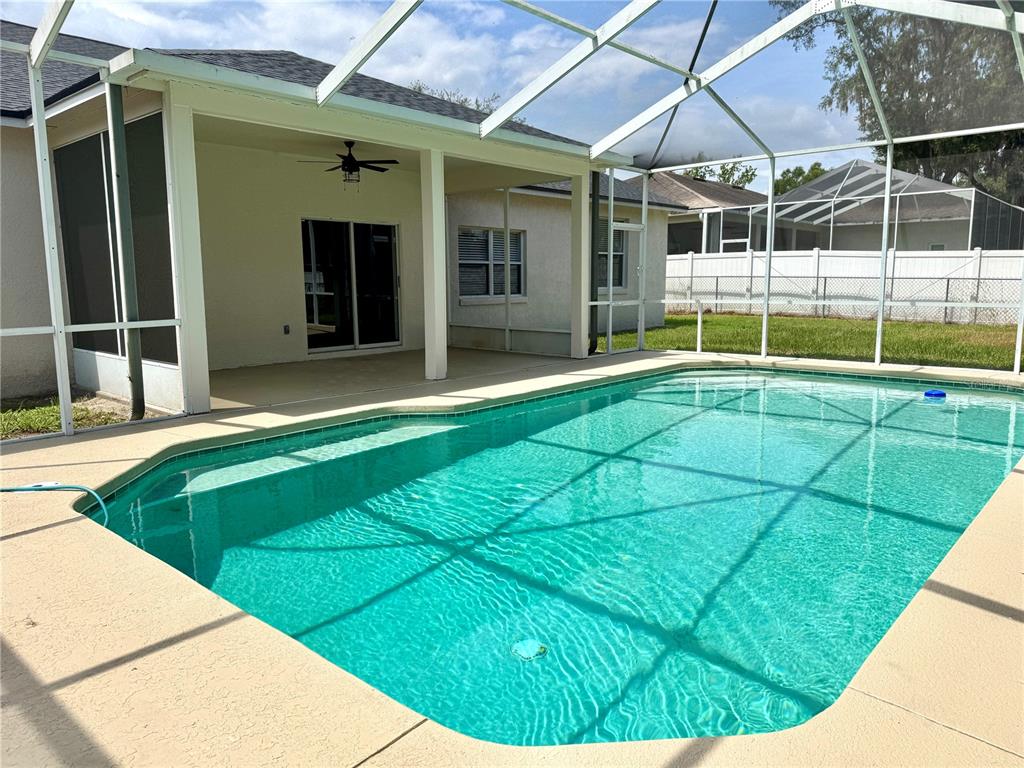 A swimming pool with a screened enclosure sits on the patio of a suburban home — 1540 WATSON OAKS COURT, LAKELAND, FL