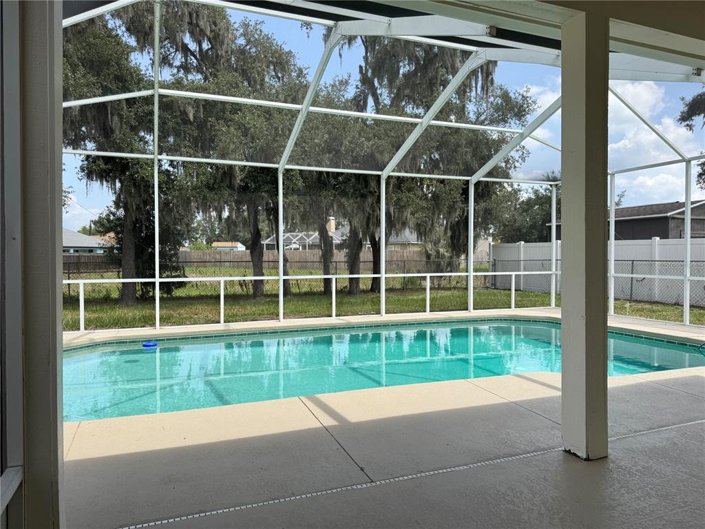 A screened-in patio features a swimming pool overlooking a grassy yard with large trees — 1540 WATSON OAKS COURT, LAKELAND, FL