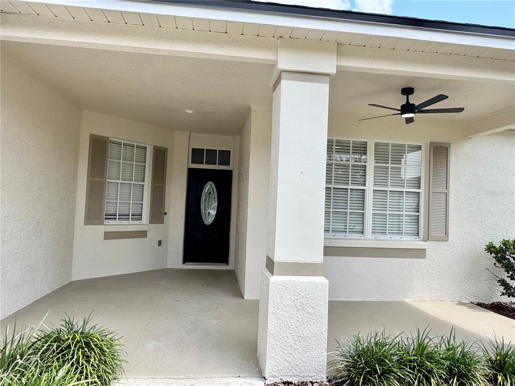 A covered front porch features a black door, a ceiling fan, and two windows with shutters — 1540 WATSON OAKS COURT, LAKELAND, FL