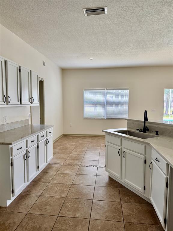 A kitchen features a light-colored stone countertop, a stainless steel sink, and a black faucet — 1540 WATSON OAKS COURT, LAKELAND, FL