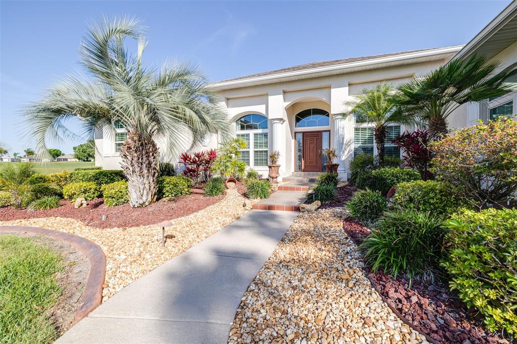 A concrete walkway leads to the front entrance of a house with a palm tree — 7042 MONTREAL DRIVE, LAKELAND, FL