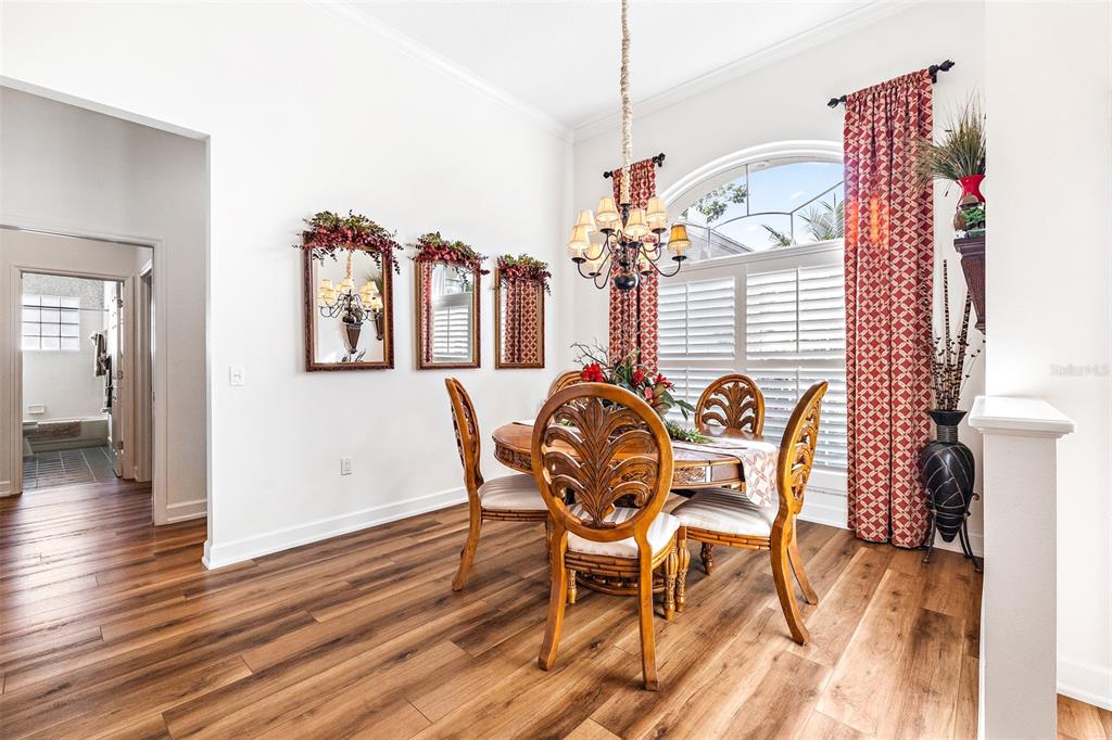 A dining room features a round wooden table, four chairs, a chandelier, and arched windows — 7042 MONTREAL DRIVE, LAKELAND, FL