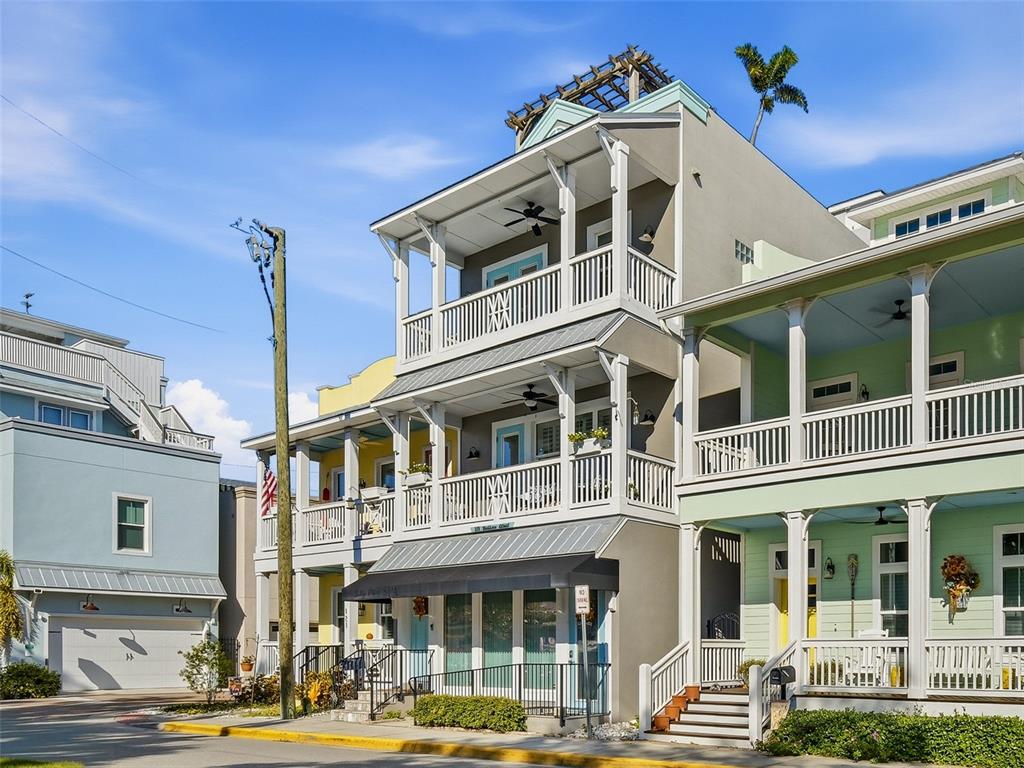 A three-story townhouse exterior features stacked balconies, a metal awning, and a rooftop pergola — 119 FAULKNER STREET, NEW SMYRNA BEACH, FL