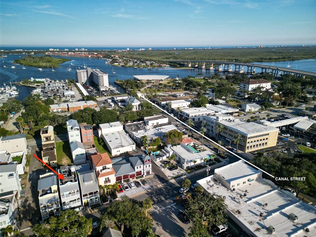 An aerial view shows a multi-story residential building with a rooftop deck near a street — 119 FAULKNER STREET, NEW SMYRNA BEACH, FL