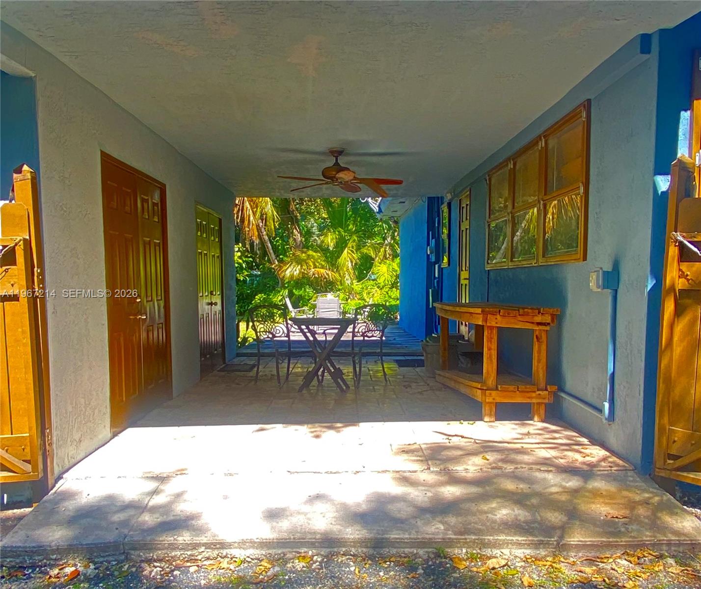 A covered patio features a ceiling fan, a wooden workbench, and a small outdoor dining set — 5975 SW 60th St, South Miami FL 33143, SOUTH MIAMI, FL