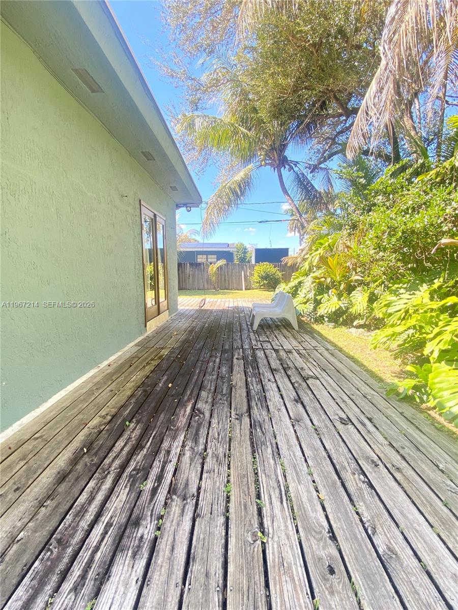 A weathered wooden deck runs alongside a light green house with a sliding glass door — 5975 SW 60th St, South Miami FL 33143, SOUTH MIAMI, FL
