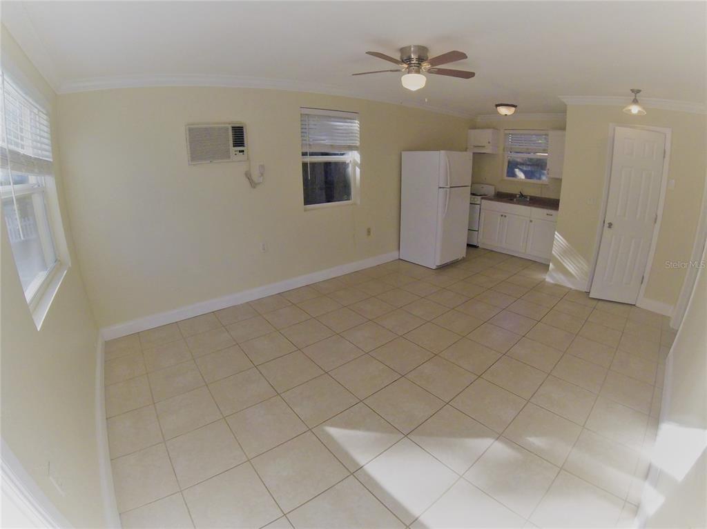 A room with light-colored tile flooring, a ceiling fan, a window unit, and a kitchen — 1300 28TH AVENUE N UNIT 2, ST PETERSBURG, FL