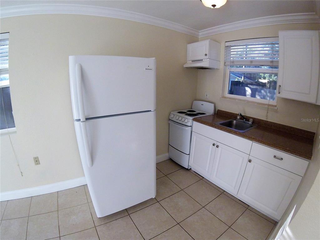 A kitchen features white appliances, white cabinets, a brown countertop, and light-colored tile flooring — 1300 28TH AVENUE N UNIT 2, ST PETERSBURG, FL