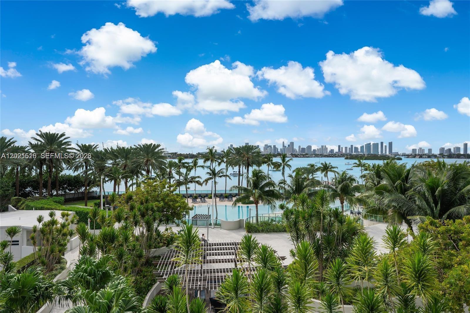 An elevated view of a swimming pool surrounded by palm trees overlooking a bay — 1500 Bay Rd # 416S, Miami Beach FL 33139, MIAMI BEACH, FL