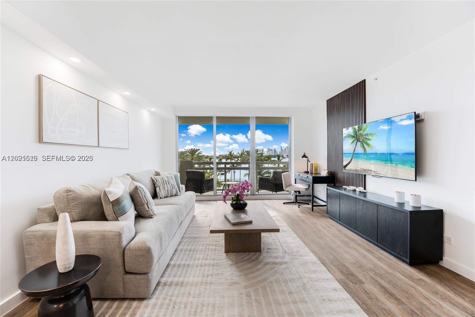 A living room features a sofa, coffee table, media console, and a balcony with water views — 1500 Bay Rd # 416S, Miami Beach FL 33139, MIAMI BEACH, FL