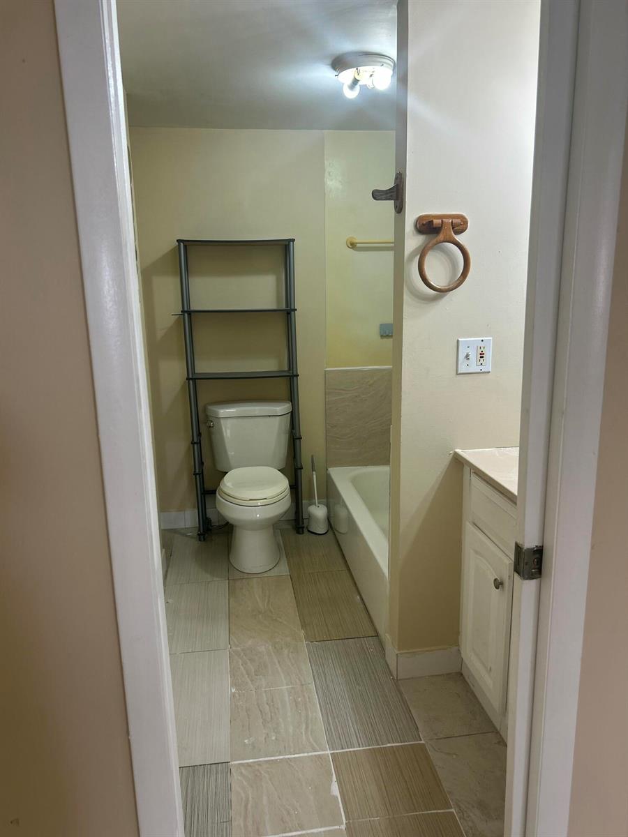 A bathroom features a toilet with a storage rack, a bathtub, and a vanity — 10331 Marlin Drive, Boca Raton FL 33428, BOCA RATON, FL