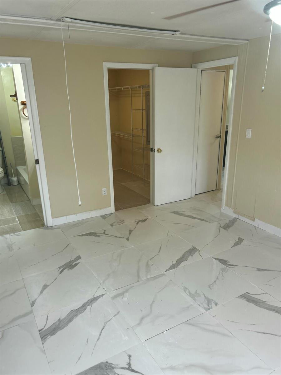 A room with white marble-patterned tile flooring, three doorways, and a walk-in closet — 10331 Marlin Drive, Boca Raton FL 33428, BOCA RATON, FL