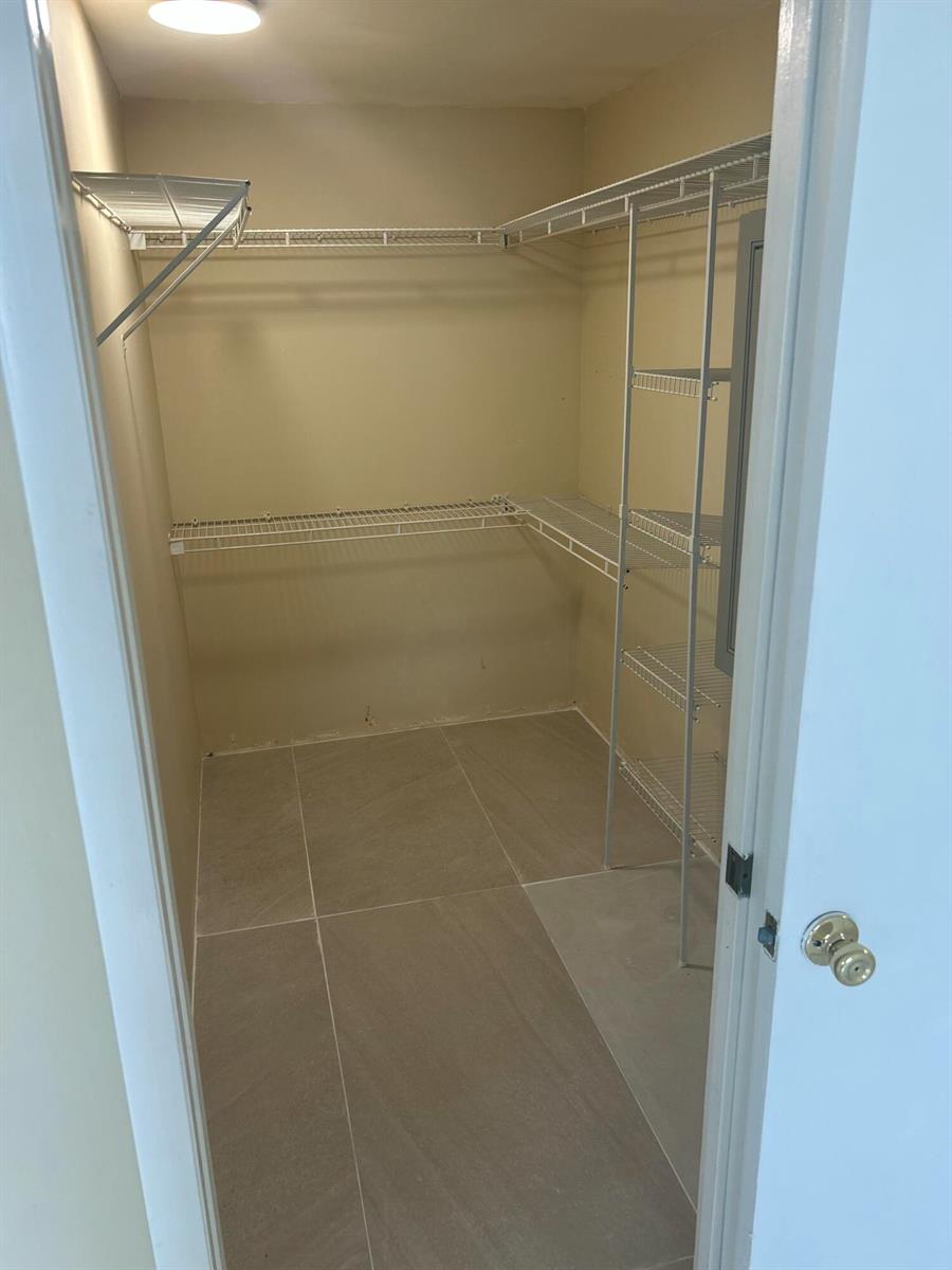 A walk-in closet features beige tile flooring, white wire shelving, and a single ceiling light — 10331 Marlin Drive, Boca Raton FL 33428, BOCA RATON, FL