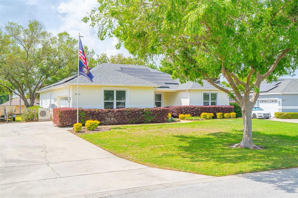 A single-story yellow house with a concrete driveway, solar panels, and a front yard — 3510 HUNTERS TRAIL CIRCLE, EUSTIS, FL