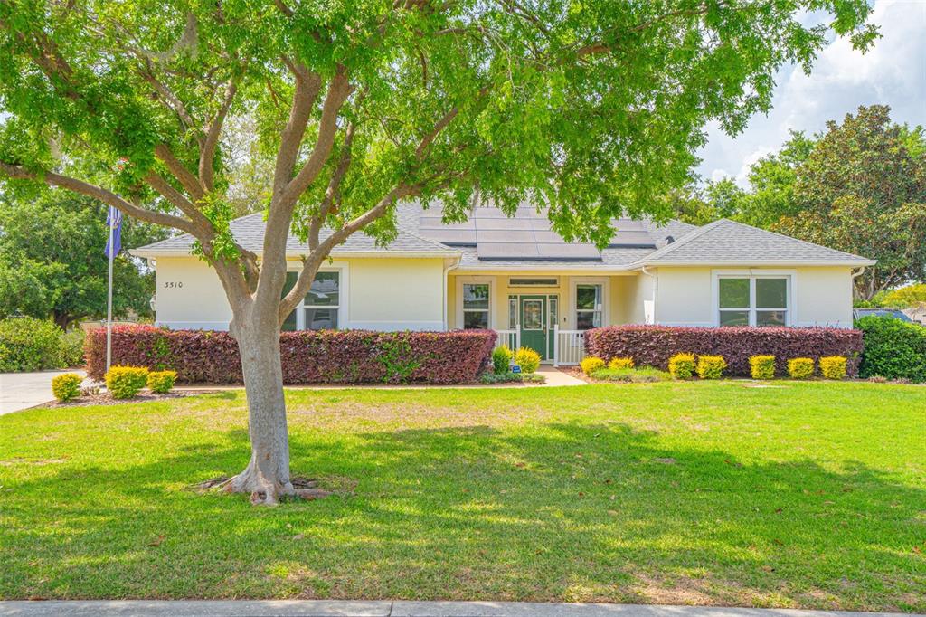 A single-story house with a yellow exterior, solar panels, and a large front yard tree — 3510 HUNTERS TRAIL CIRCLE, EUSTIS, FL