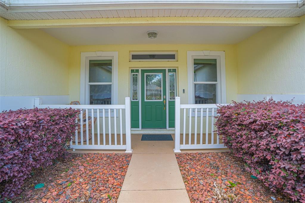 A front porch with a green door, white railing, and red landscaping rocks — 3510 HUNTERS TRAIL CIRCLE, EUSTIS, FL